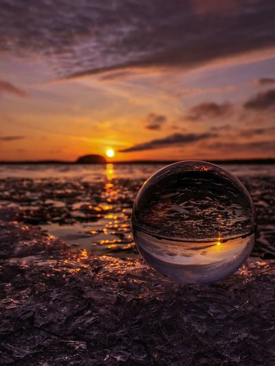 Glass on beach against sky during sunset