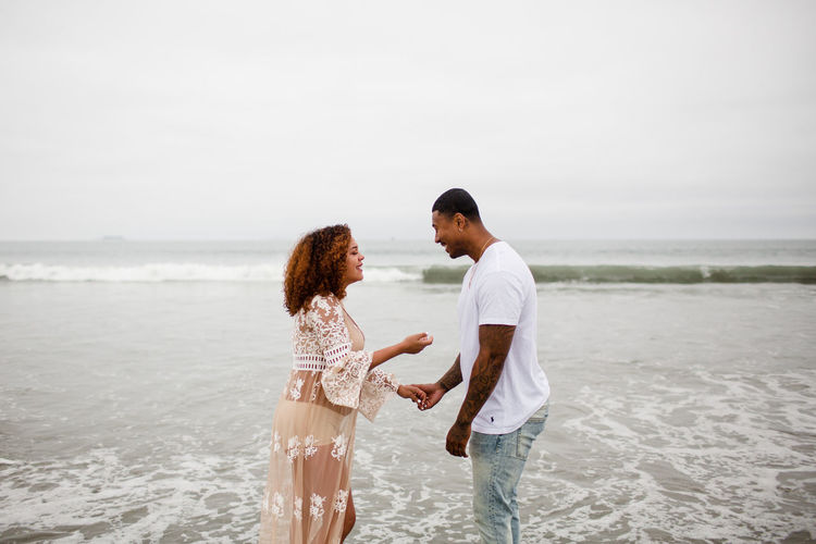 Mixed race couple posing on beach, maternity
