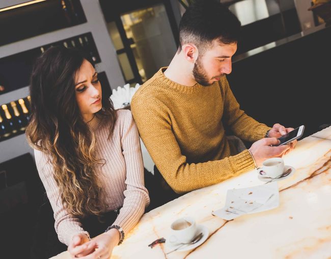 Couple using phone while sitting in cafe