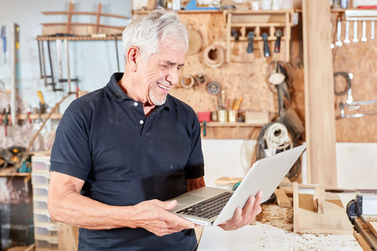 Smiling man with laptop in workshop