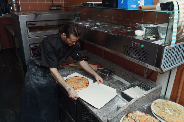 Male chef packing pizza in restaurant kitchen