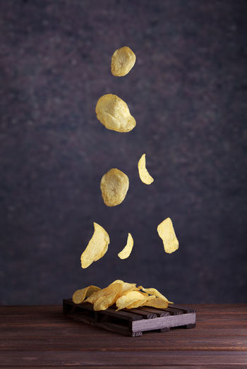 Potato chips fall into a clay bowl on a gray background. flying chips closeup.