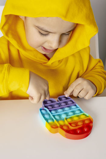 Little boy plays with rainbow pop it fidget toy. antistress children game. children's trendy toys 