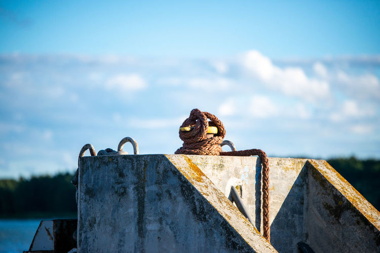 View of bird perching on rusty metal against sky