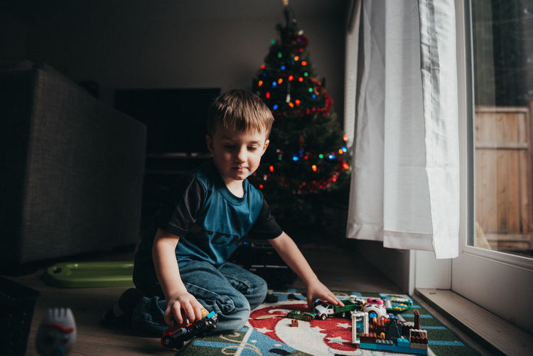 Boy sitting in christmas tree at home