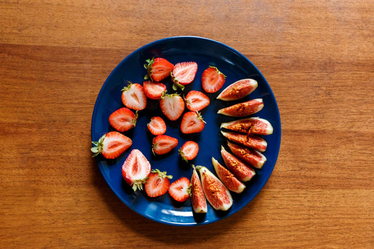 The plate of fresh tasty slices of fruits such as strawberry and fig