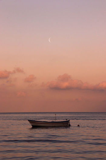 Boat in sea against sky during sunset