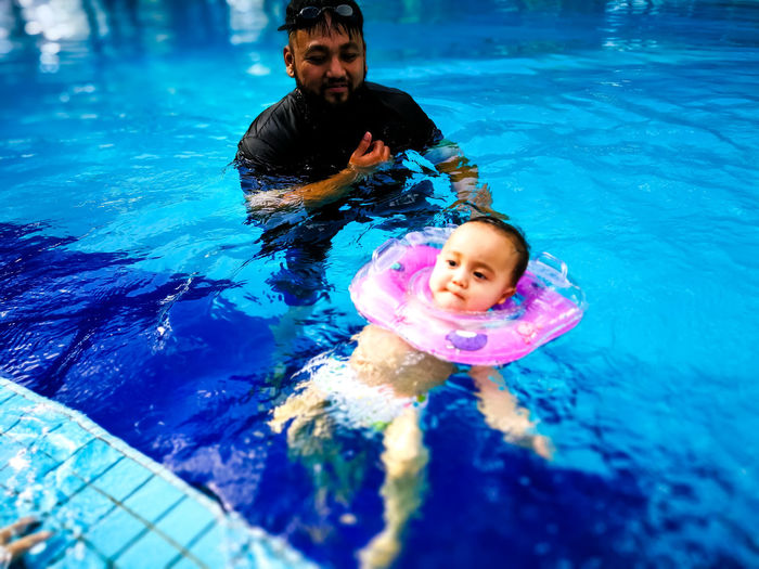 Father swimming with baby in pool