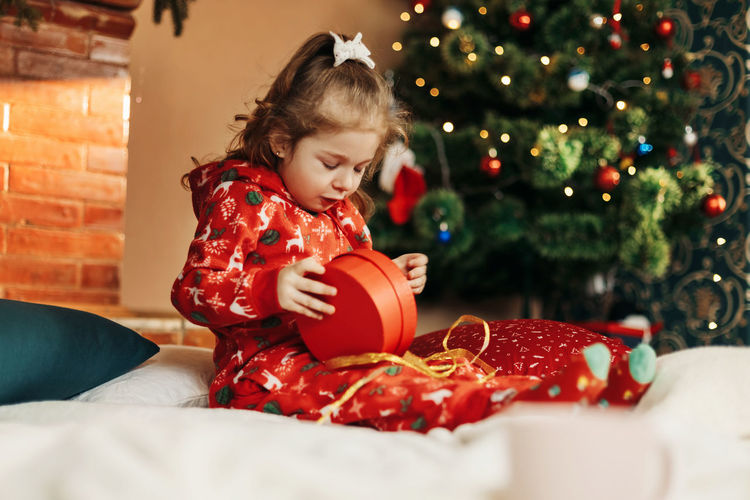 Portrait of smiling girl playing with christmas tree at home