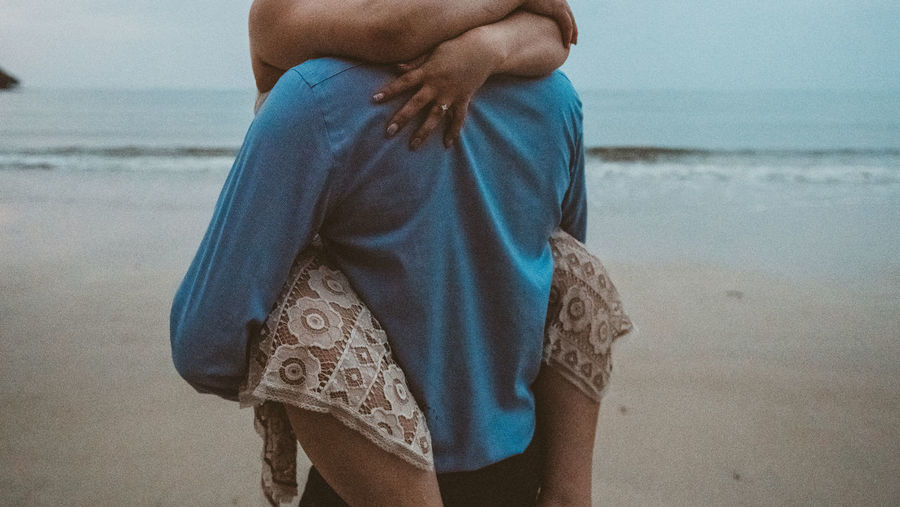 Midsection of romantic couple embracing at beach