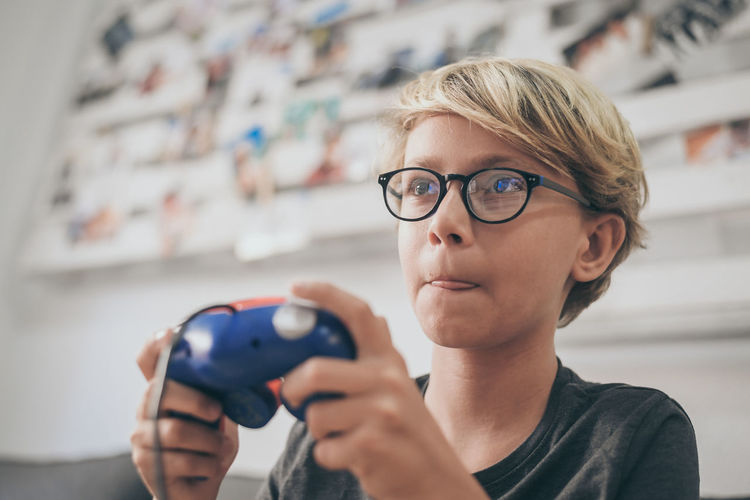 Close-up of boy playing video game in living room at home