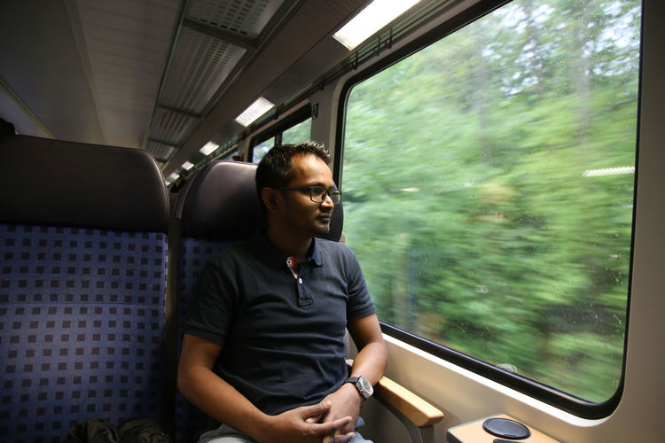 Full length of young man sitting in train in german train during day