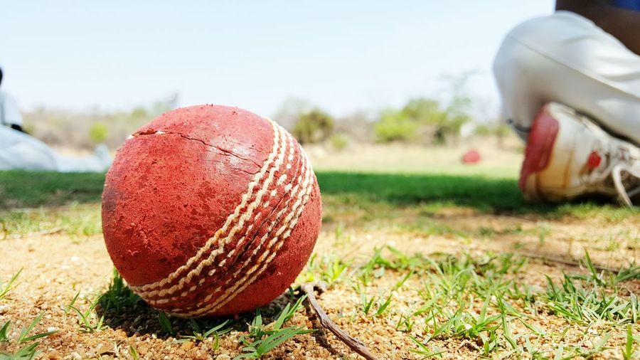 Close-up of cricket ball on field during sunny day
