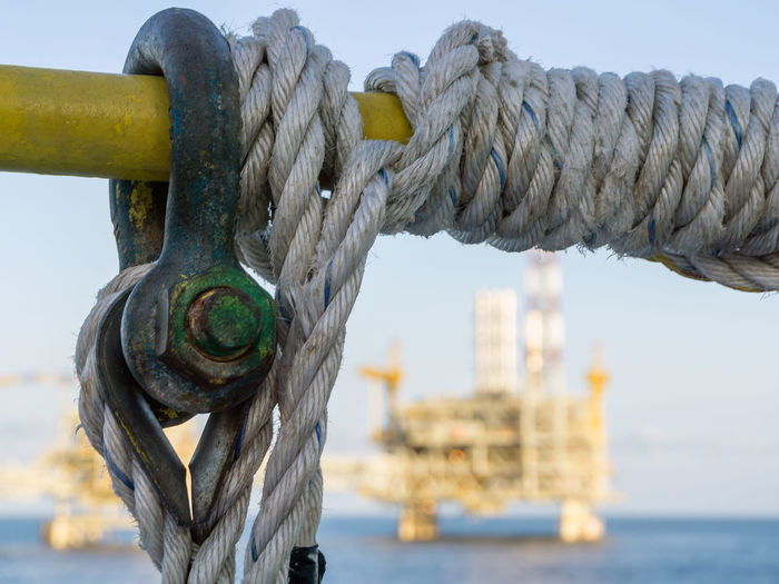 Shackle and rope coiled on a handrail of a construction work barge at oil field
