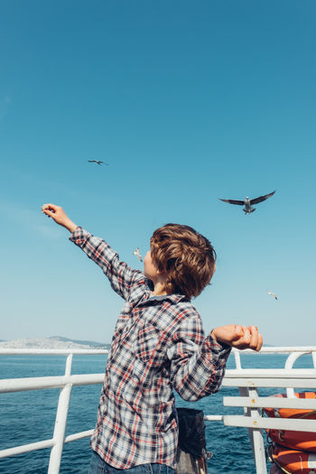 Boy traveling on a ferry and feeding wild birds.