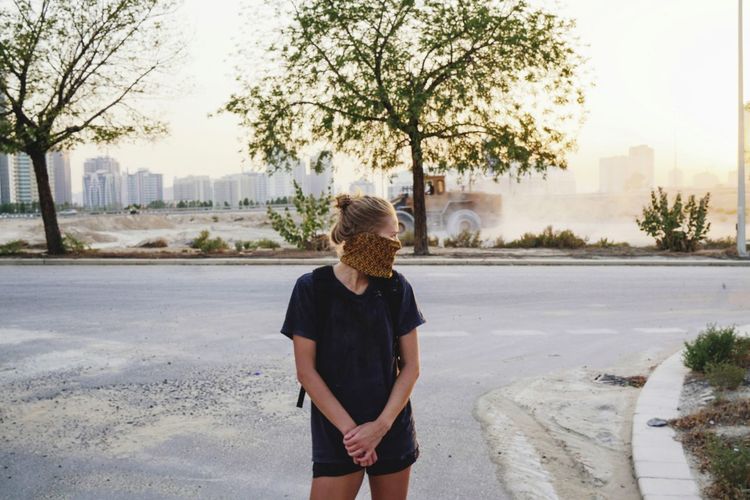 Woman standing on the dusty street wearing mask