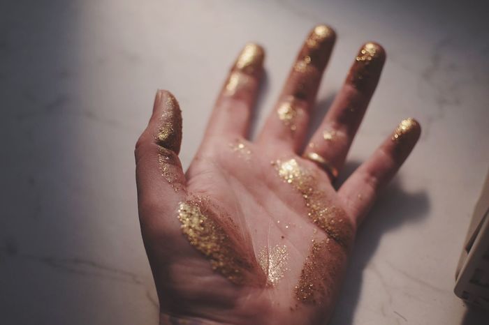 Cropped image of woman hand covered with glitter on marble