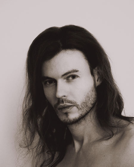 Portrait of man with long hair against white background