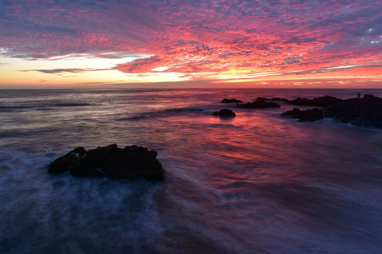 Scenic view of sea against cloudy sky during sunset