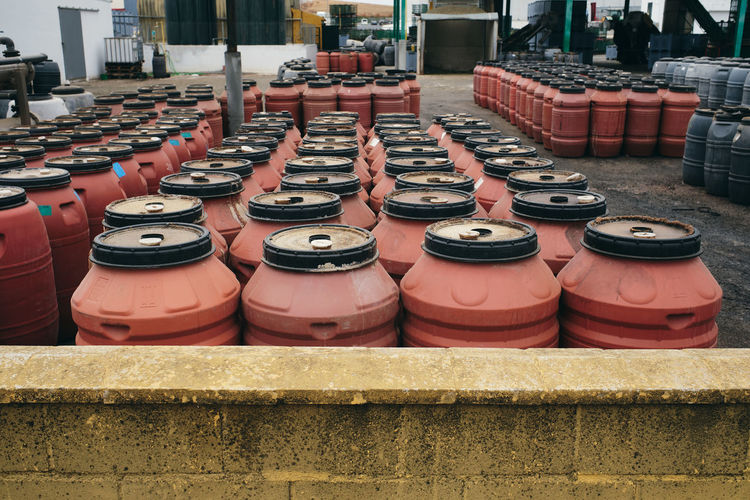 Rows of grungy metal barrels arranged in shabby warehouse in industrial facility at factory