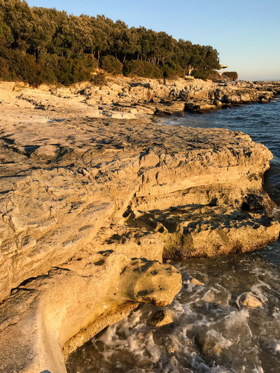Rock formation on beach against sky