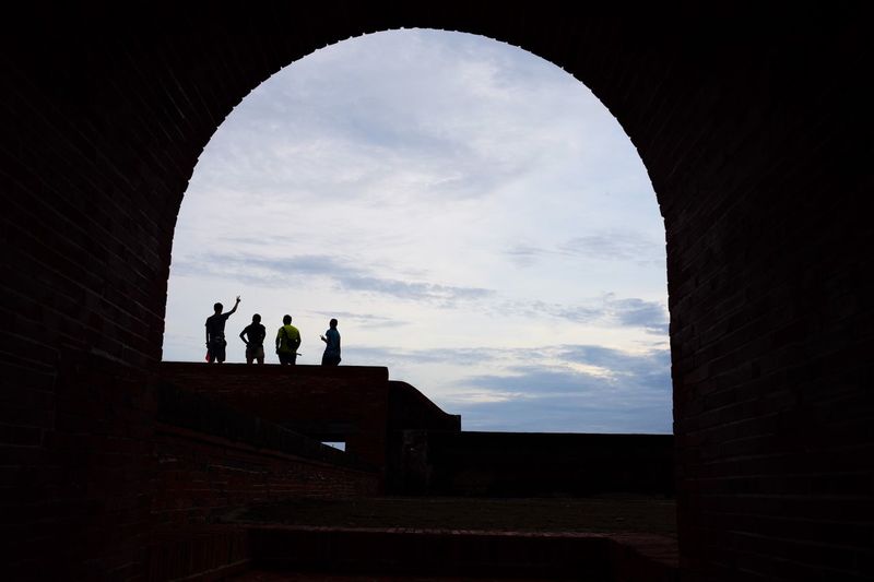 Low angle view of silhouette people standing against sky