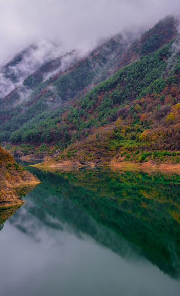 Scenic view of lake by mountain against sky