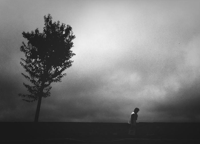 Silhouette of people standing on landscape against cloudy sky