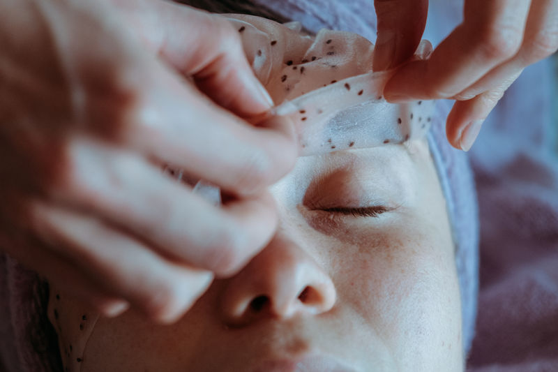 Close-up portrait of young woman applying peel off mask for facial cleansing and spa treatment.