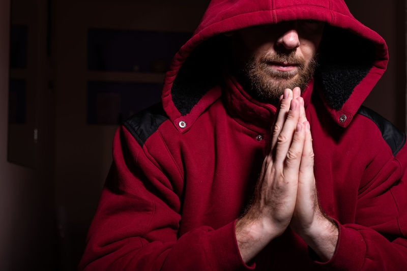 Man wearing hoodie with clasped hands