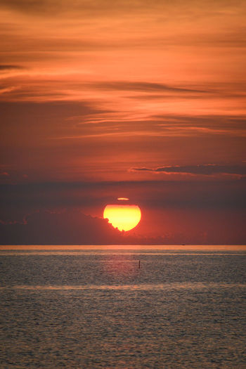 Scenic view of sun and sea against orange sky
