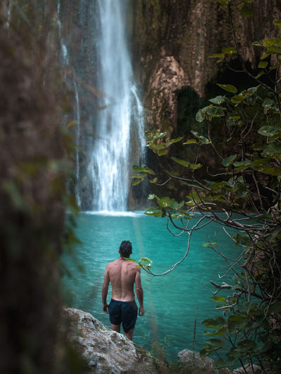 Full length of shirtless man waterfall in forest