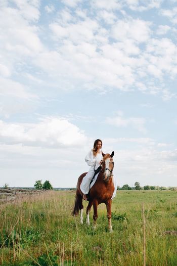 Young woman riding horse on field
