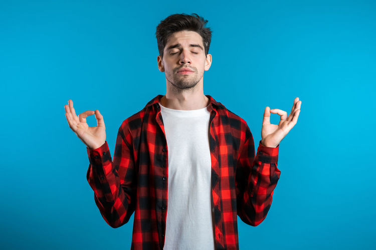 Young man standing against blue background