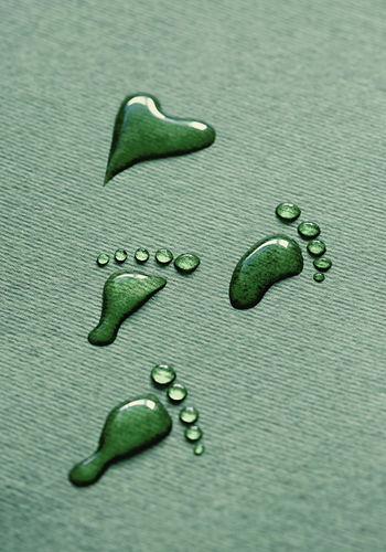 Water footprints from drops, on a green background. drops of water that look like bare footprints.
