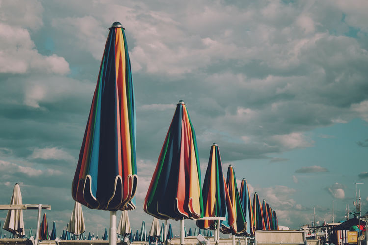 Low angle view of beach umbrellas against cloudy sky