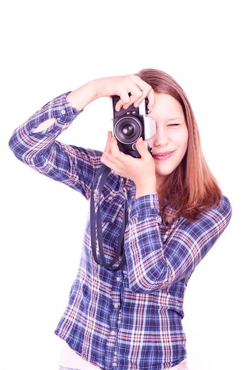 Portrait of smiling young woman photographing against white background
