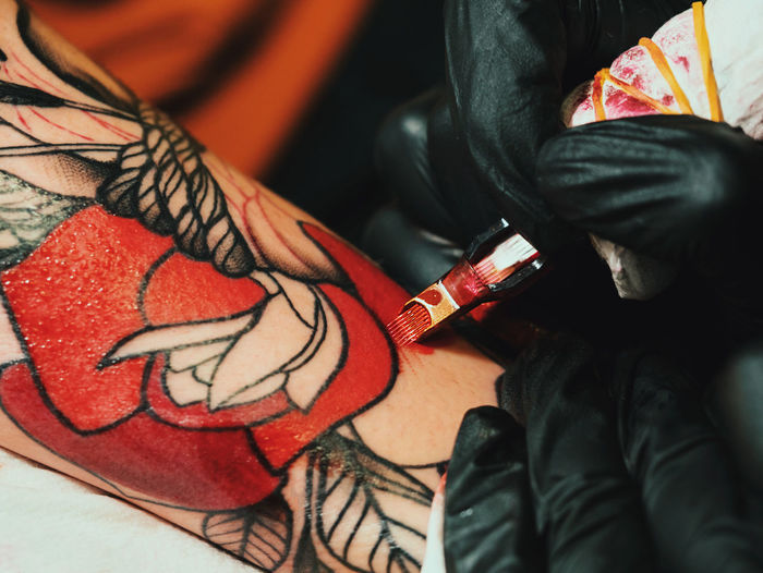 Cropped image of female artist making tattoo on male customer hand