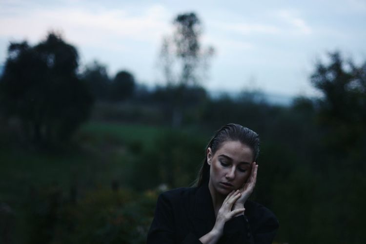 Woman with eyes closed standing in forest
