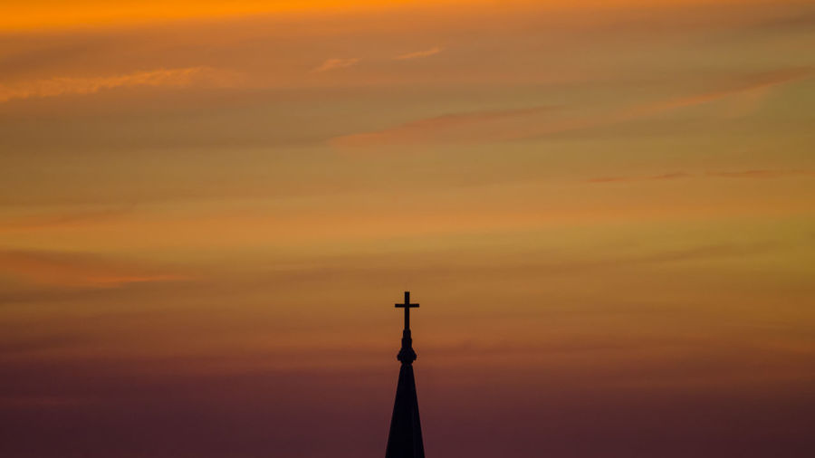Cross on top of church against sky during sunset