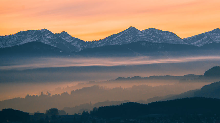 Scenic view of mountains against dramatic sky during sunset