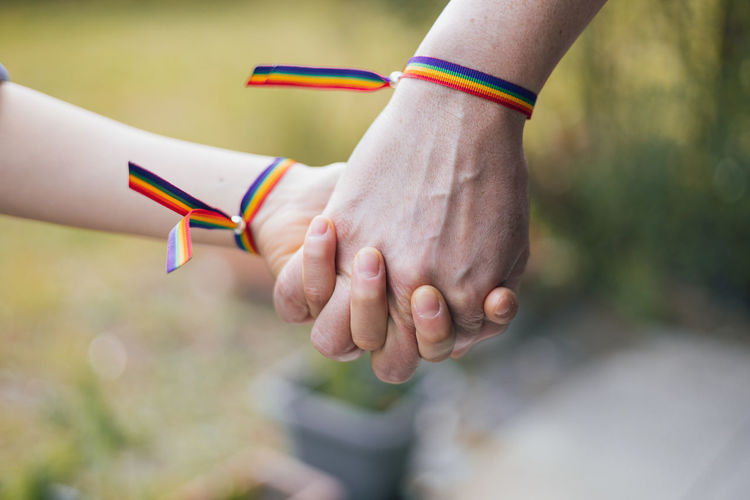Mother and daughter holding hands with a rainbow-bracelet