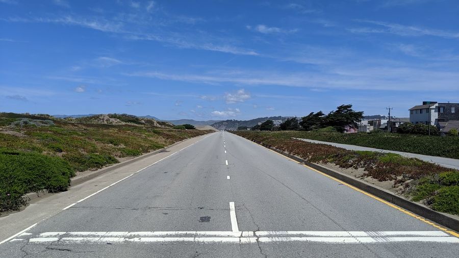 Road passing through city against sky