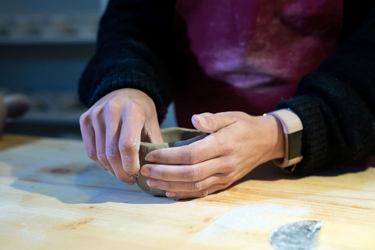 Young ceramist woman shaping ceramic bowl in pottery workshop