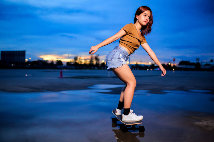 Asian women playing surf skate or skates board outdoors.