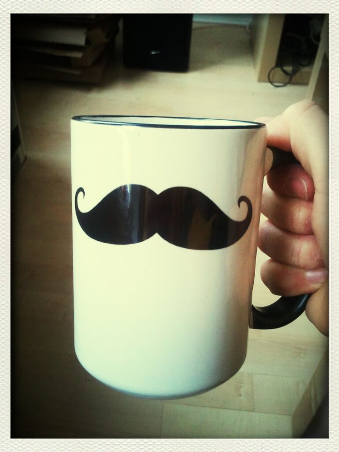 Cropped image of hand holding coffee cup with mustache