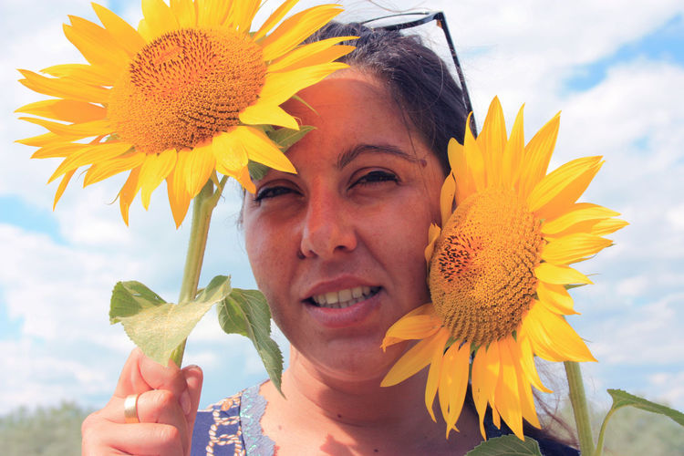 Happy nice woman caucasian girl in the center between two yellow sunflower plants in a field