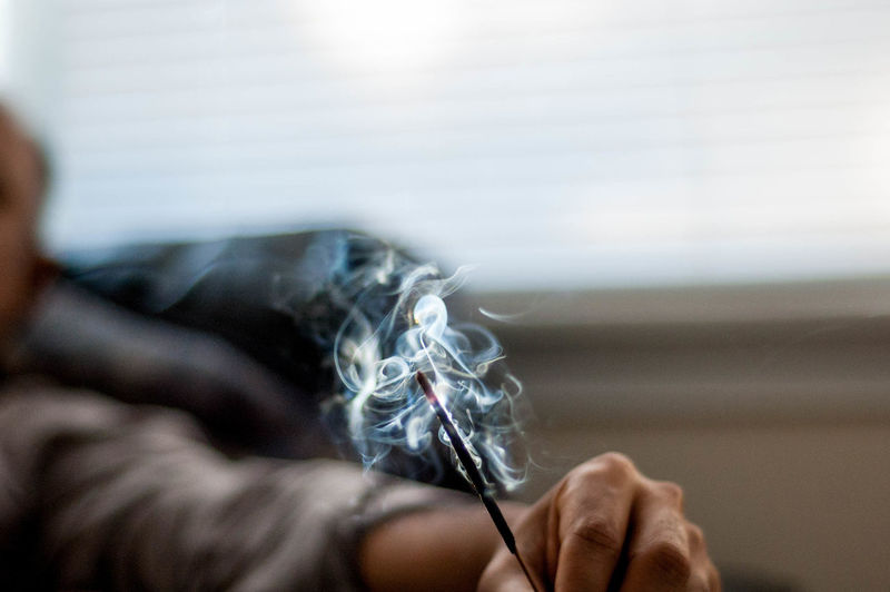Cropped image of man holding incenses at home