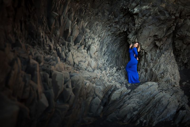 Model wearing blue dress standing on rock formation