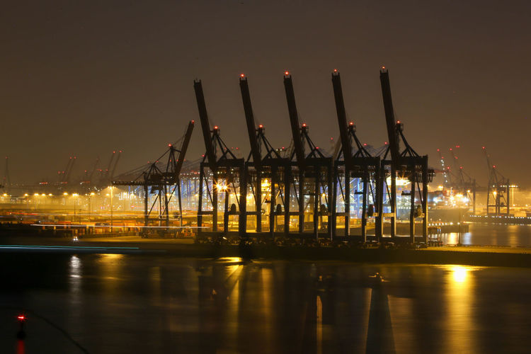 Illuminated pier at harbor during night